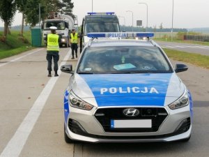 Funkcjonariusze Ruchu Drogowego KPP w Działdowie i Inspekcji Transportu Drogowego z Iławy podczas kontroli pojazdu ciężarowego, na pierwszym planie widać policyjny radiowóz, z tyłu funkcjonariuszy Policji i ITD