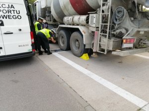 Funkcjonariusze Ruchu Drogowego KPP w Działdowie i Inspekcji Transportu Drogowego z Iławy sprawdzają stan techniczny - koła i opony pojazdu ciężarowego zatrzymanego do kontroli drogowej