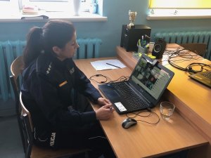 Policjantka siedzi na krześle przed ekranem laptopa i prowadzi rozmowę online z rodzicami uczniów szkoły podstawowej
Policjantka siedzi na krześle przed ekranem laptopa i prowadzi pogadankę online z uczniami szkoły podstawowej
Policjantka stoi na dywanie, ma założoną maseczkę przykrywającą usta i nos, przed nią na dywanie siedzą dzieci i trzymają w rękach elementy odblaskowe
