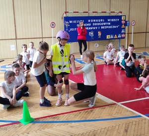 dzieci podczas jednej z konkurencji zakładają elementy wyposażenia rowerzysty