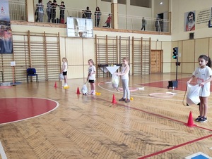 dziewczynki stoją za linią z workami zawierającymi elementy wyposażenia rowerzysty podczas jednej z konkurencji sportowych