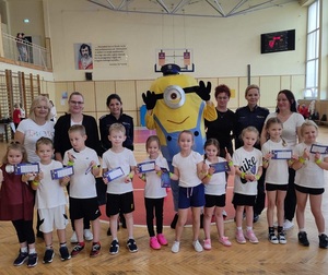 jedna z drużyn biorących udział w konkursie na zdjęciu grupowym z maskotką Minionkiem, opiekunem, organizatorkami konkursu i policjantkami
