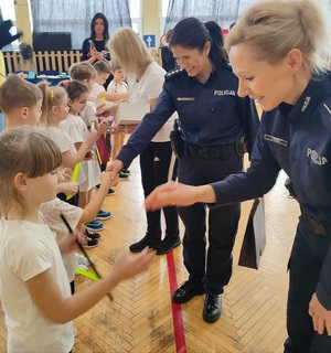 policjantki podczas przekazywania dzieciom elementów odblaskowych i gratulacji