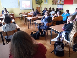 uczniowie podstawówki oglądają w klasie film edukacyjny w obecności policjantki