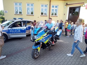 chłopiec na motocyklu policyjnym obok radiowóz policyjny i dzieci